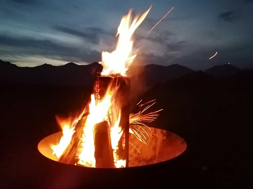 Ein Feuer lodert spät abends in der Feuerschale vor der Alphütte Schlafegg